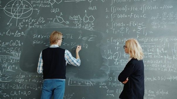 Schüler und Lehrkraft vor Tafel